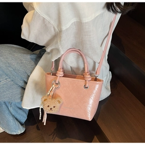 Pink lychee texture tote bag with brown plush bear charm worn by model in lifestyle scene