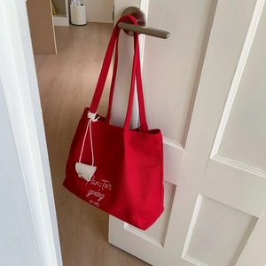 Detail of red canvas tote bag with white embroidery and mini earphone pouch charm