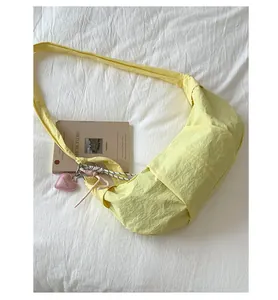 Detail der hellgelben Nylon-Tasche mit Herzanhänger und gewebter Seildekoration