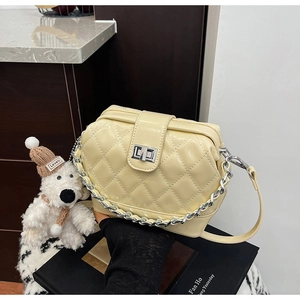 Close-up of cream quilted leather handbag with silver chain strap and metal lock detail