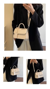 Detail of the cream-white faux leather handbag featuring woven texture and smooth stitching