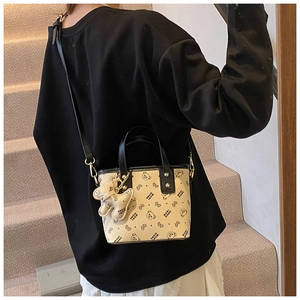 Close-up of cream leather bag with black bear prints and cute 3D bear charm accessory