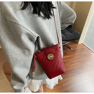 Détail du sac seau rouge tressé avec pendentif cacahuète dorée et fermoir métallique