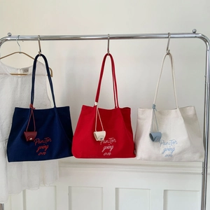 Minimalist canvas tote bags in navy, red, and beige with leather pendants on a hanger