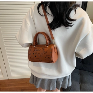 Back view of model carrying a brown Boston barrel bag with cute animal prints and golden hardware