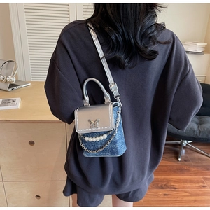 Mini borsa a tracolla in denim con patta argentata e catena di perle indossata da modella