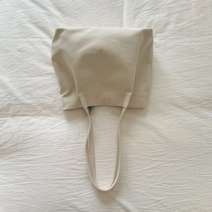 Detail view of large beige canvas tote bag with thick woven texture and sturdy shoulder straps