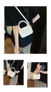 Detail of a creamy white structured square bag showing lychee grain leather and handles