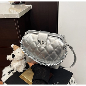 Detail of silver quilted handbag with metal texture, turn-lock closure and chain strap