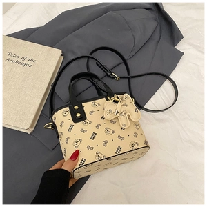 Detail of off-white bucket bag with bear patterns and cute teddy charm accessory