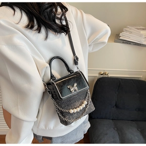 Close-up of black glitter crossbody phone bag featuring a metal butterfly and pearl chain