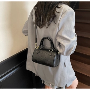 Detailed view of black Boston bag with embossed bear pattern on a lifestyle model