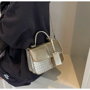 Close-up of golden metallic handbag with mixed smooth and woven texture flap