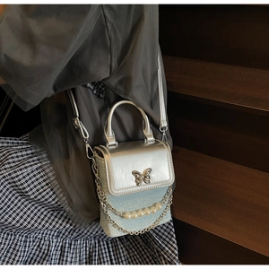 Dettaglio della mini borsa a tracolla con chiusura a farfalla argentata e perle decorative