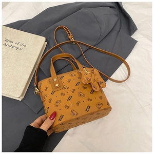 Detailed view of the tan bucket bag featuring a cute cartoon bear print and branding text