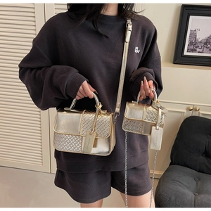 Detailed view of two gold metallic crossbody bags with woven patterns and chain straps