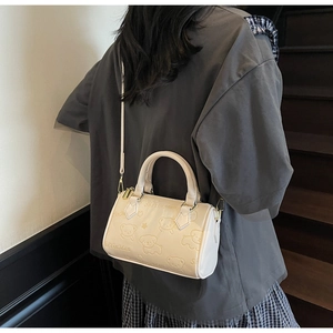 Detail of cream Boston bag with bear embossing and gold zipper on a female model