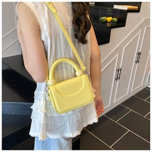 Chic lemon yellow crossbody bag with unique round handle and decorative beige ball accents