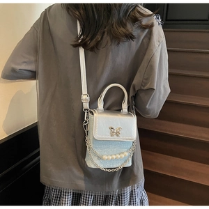 Detail of mini crossbody bag with silver butterfly clasp and pearl chain shoulder strap
