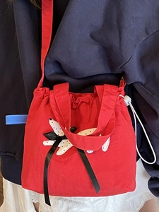 Borsa a secchiello rossa con toppa a fiore bianco e fiocco nero con coulisse