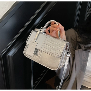 Detail of silver metallic handbag showing intricate woven patchwork and smooth leather texture