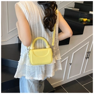 Close-up of a trendy yellow mini crossbody bag with textured leather and silver buckle