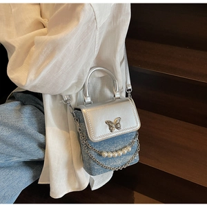 Close-up of denim and silver crossbody phone bag with pearl chain and butterfly buckle