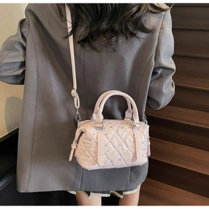 Detail of pink quilted handbag with crystals worn crossbody over a grey oversized blazer