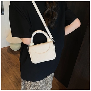 Detail of crossbody bag with marble orb handle and lychee grain texture finish