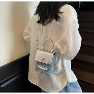 Detail of silver metallic and blue denim mini bag with butterfly and pearl chain