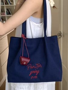 Modern navy canvas tote bag with red embroidery and a leather accessory on shoulder