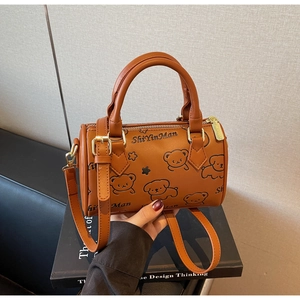 Detail of caramel brown Boston bag with cartoon dog motif and golden metal hardware accessories