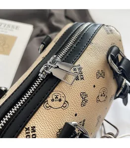 Detailansicht der silbernen Reißverschlüsse und Bärenprint auf beiger Tasche