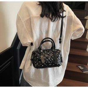 Detail of black quilted leather handbag with silver studs on a stylish wooden staircase