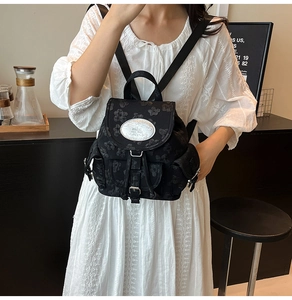 Détail du sac à dos noir brodé de fleurs avec étiquette de marque et cordon serrage