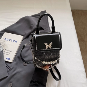 Detail of tweed phone bag with silver butterfly charm and pearl chain decoration