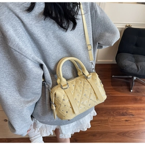 Detail of yellow quilted Boston bag with sparkling rhinestones and silver hardware
