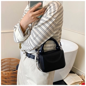 Detail of black pebbled leather handbag with thick round handle and silver hardware