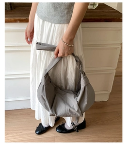 Detail of grey hobo bag showing the knotted handle and metallic ring buckle design