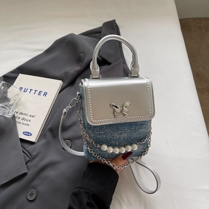 Detail of silver butterfly buckle and pearl handle on denim mini crossbody phone bag