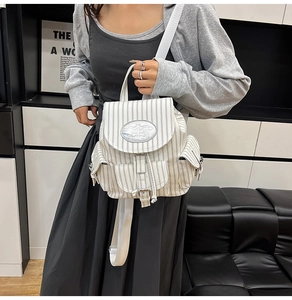 Gros plan d'un mini sac à dos rayé avec plusieurs poches porté par un mannequin