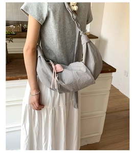 Detail of grey nylon half-moon bag featuring elegant pleated texture and pink heart charm