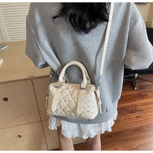 Close-up of quilted cream Boston bag with sparkling silver rhinestones and long strap