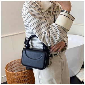 Litchi texture black crossbody bag detail showing spherical handle and leather strap