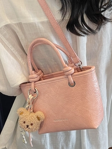 Pink litchi texture mini tote bag with teddy bear charm and adjustable shoulder strap