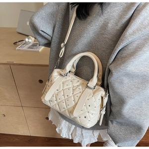 Dettaglio della borsa trapuntata color crema con strass scintillanti e dettagli in argento