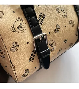 Nahaufnahme der beigen Tasche mit Bärenmuster, Lederriemen und silberner Gürtelschnalle