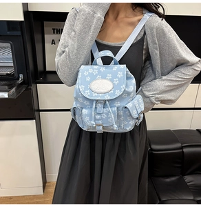 Détail d'un mini sac à dos bleu clair à fleurs avec cordon de serrage et poches latérales