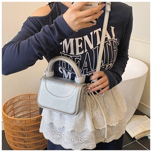 Detail of silver metallic mini square bag featuring fine grain texture and sturdy handle