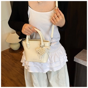 Détail du sac à main blanc crème avec breloque cœur en perles et nœud en dentelle